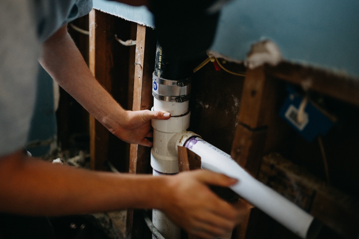 New pipe being fitted between wall studs during a repair by Matlock Rooter Services